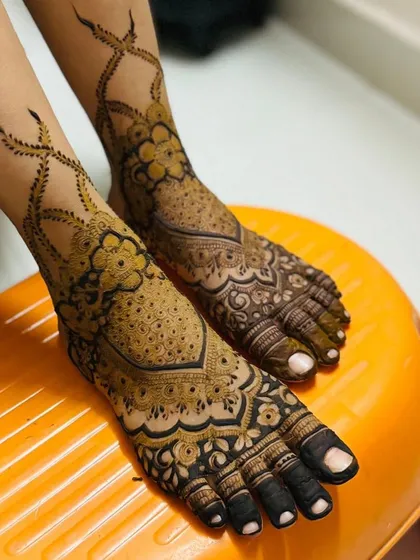 Bridal mehendi isn't complete without adorning the feet. This design features intricate floral and vine work that elegantly wraps around the ankle, ensuring you look beautiful from every angle on your special day.