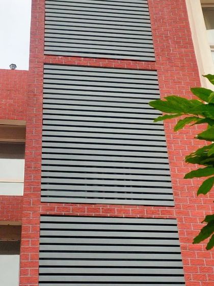 These horizontal metal louvers create a modern, segmented look on this brick building. They are perfect for hiding service areas or adding a design element to a flat exterior wall.