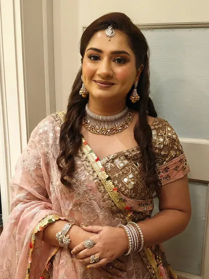 A close-up of the HD party makeup and half-up hairstyle. The soft curls and maang tikka create a beautiful, festive frame for her face.