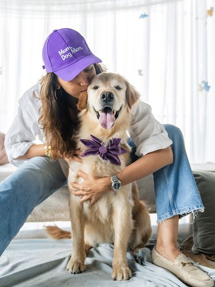 "Dog Mom" and proud! A woman wearing a "Dog Mom" cap shares a loving hug with her Golden Retriever during a special Mother's Day studio session.