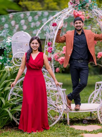 A fun and happy couple poses with our fairytale Cinderella carriage, which is nestled among the flowers and greenery of the garden.