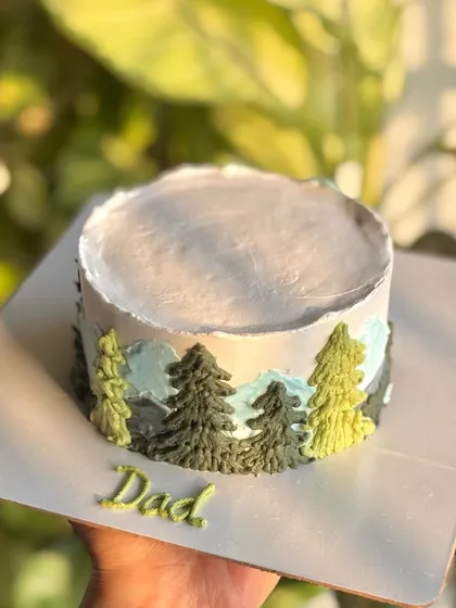 A hand-held shot of the mountain-themed bento cake, showing its artistic design and personal touch for "Dad."