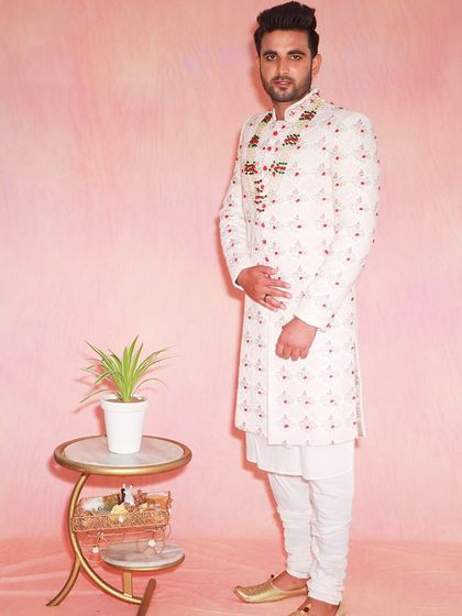 This sherwani features beautiful floral embroidery on the collar and is paired with a simple white kurta. It's a great rental choice for a sophisticated and stylish groom.