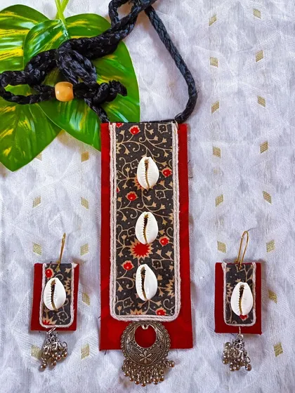A clear, well-lit shot of the Kalamkari and cowrie shell necklace set. This view shows the texture of the fabric and the metallic sheen of the oxidized silver charm.