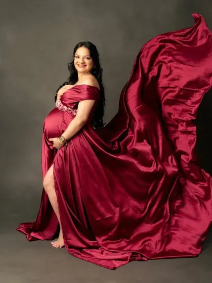 The flowing train of this burgundy satin gown creates a beautiful sense of movement, perfect for a dynamic and glamorous maternity photo.