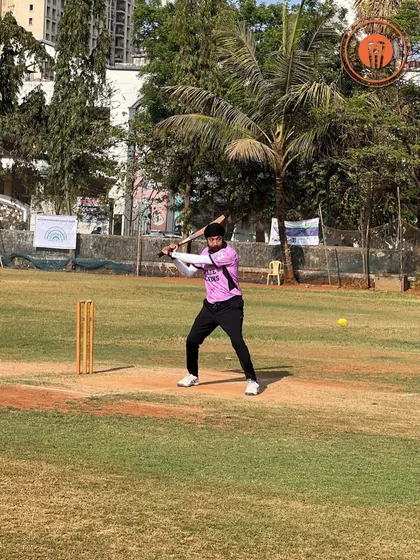 A batsman in a pink jersey swings hard at the ball during an intense PPL match.