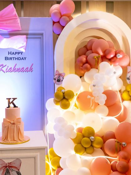 A detailed shot of the stunning balloon cascade and bow-themed cake, showing the intricate design and soft color palette.