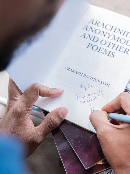 A close-up shot of an author's hand as they write a personal note in their book, a simple yet powerful image of connection.