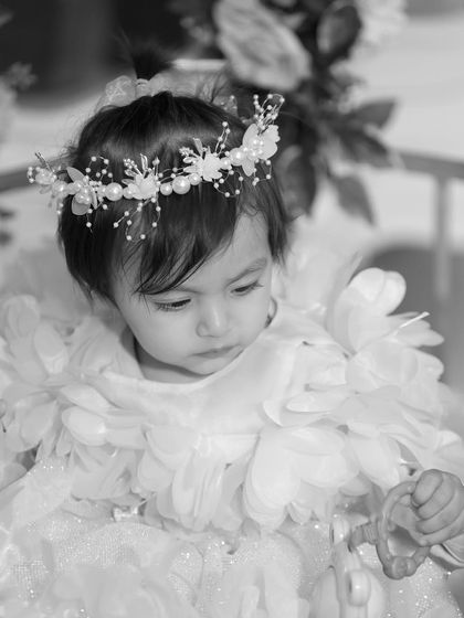 A beautiful black and white portrait of a little girl in a delicate dress and floral crown, giving the image a timeless, angelic quality.