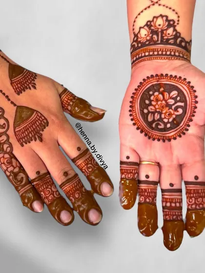 This design shows two different styles for each hand. One features a traditional floral mandala, while the other has a more contemporary layout with hanging jhumka motifs.