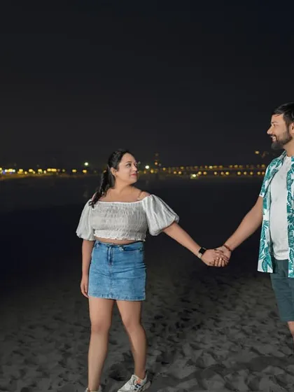 A romantic walk on the beach at night. The simplicity of the scene, with just the couple and the distant lights, makes their connection the main focus.