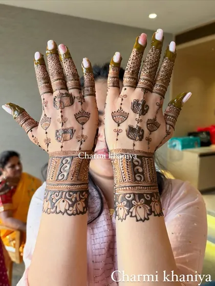 A perfect henna design with hanging motifs. The wrist cuffs are filled with intricate patterns, balancing the delicate design on the palm.