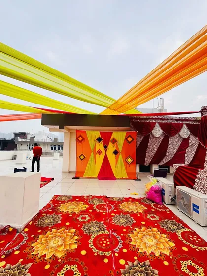 A wide shot of the rooftop Haldi setup, showing the seating arrangement and the backdrop. I can transform any space, big or small.