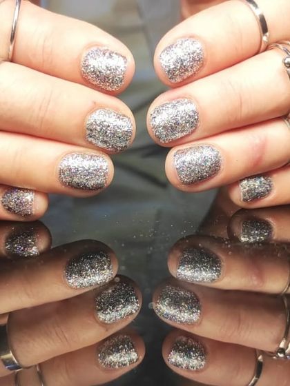 A full set of dazzling silver glitter nails on short, rounded nails for maximum sparkle.