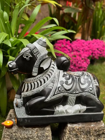 Here is a majestic seated Nandi, Lord Shiva's sacred mount, symbolizing strength and devotion. This piece is carved from a single block of stone with extensive detailing on the adornments, making it a powerful guardian for a temple-inspired entrance.