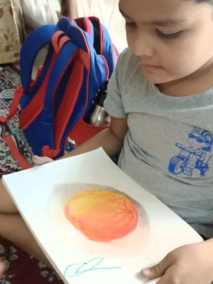 Nothing makes us prouder than seeing a student's face light up with their finished artwork. This young artist proudly displays his skillfully shaded pastel drawing of a mango, a testament to the confidence and ability gained in our classes.