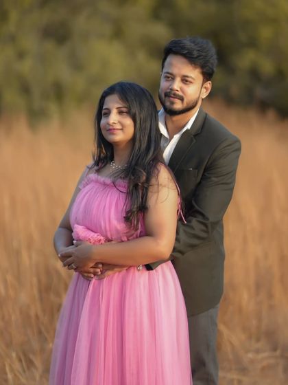 A sweet and intimate pose during a maternity photoshoot. The off-shoulder pink gown is a popular choice for its romantic and flattering style.