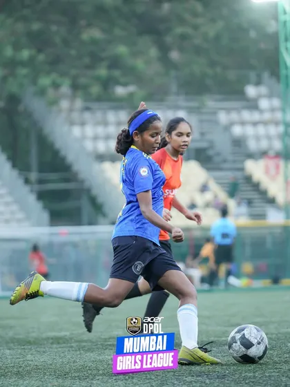 A female player makes a powerful run with the ball, leaving a defender behind. This action shot highlights the speed and attacking prowess of our girls' team members.