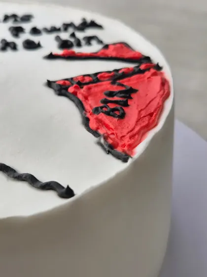 A close-up of a funny and savage birthday cake, showing the hand-piped illustration and text.