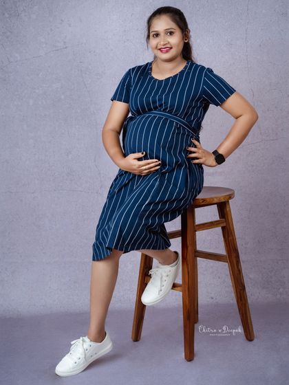 A casual and cool maternity look. A simple striped dress and sneakers show that you can be comfortable and stylish for your shoot.
