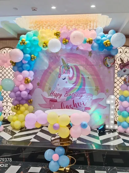 A full view of the unicorn first birthday setup, featuring a large light-up number '1' and a cake table ready for celebration.