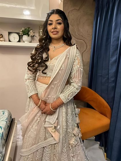 A full-length view of the stunning silver-white lehenga. The makeup is glamorous yet sophisticated, perfect for an evening of celebration.