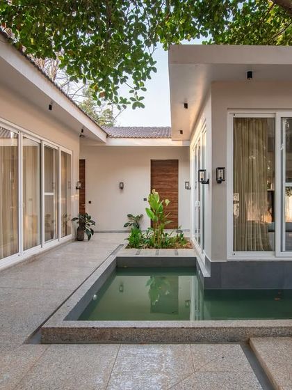 Serenity by day at The Amberle Resort in Yelagiri. The design features a central courtyard with a plunge pool, creating a private oasis that is visually connected to the surrounding rooms through large glass windows.