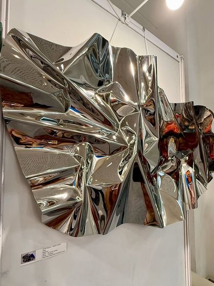The reverse side of the sculpture reveals the intricate, hand-formed folds of the stainless steel.