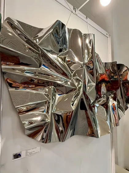 The reverse side of the sculpture reveals the intricate, hand-formed folds of the stainless steel.