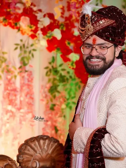 A happy and relaxed portrait of the groom. His genuine smile shows his excitement and joy, captured against a beautiful floral backdrop.