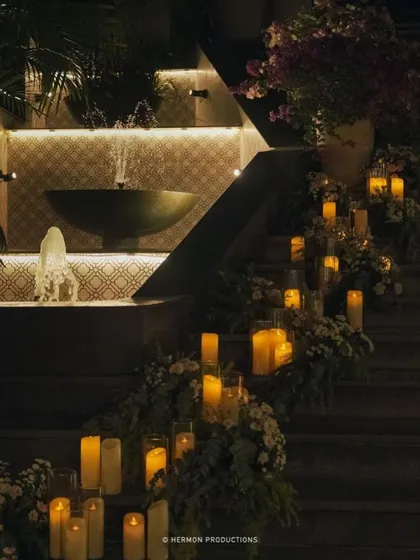 A staircase lined with candles in glass hurricanes and floral arrangements, creating a romantic and dramatic effect.