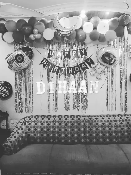 A black and white shot highlighting the composition of the space-themed wall decor, including the banner, name, and character balloons.