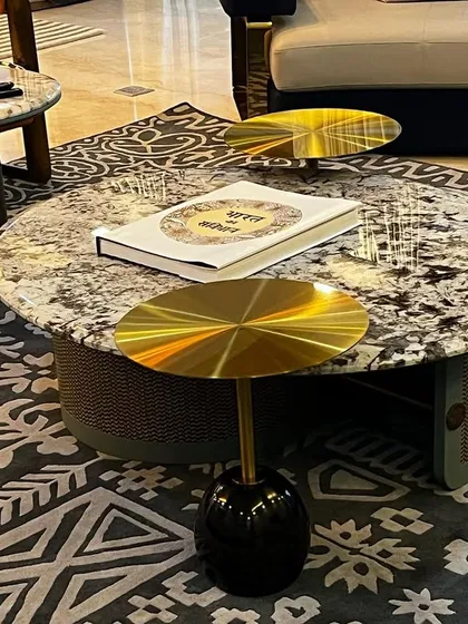 A close-up of the coffee table arrangement in the Vasant Kunj farmhouse. We layered multiple tables of different heights and materials, including stone and polished brass, to add visual interest and functionality to the seating area.