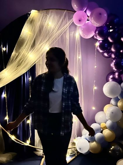 A guest enjoying a quiet moment in front of the draped arch with fairy lights. The soft lighting is perfect for taking beautiful, atmospheric photos.