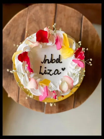 A simple birthday cake made beautiful with a scattering of fresh, colorful rose petals and baby's breath.