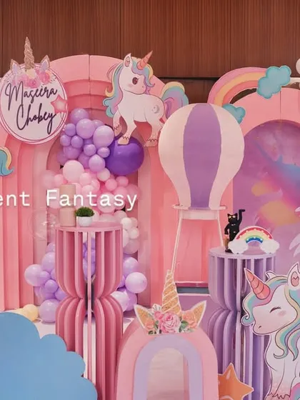 Another view of the unicorn party stage, showing the different unicorn cutouts, a hot air balloon prop, and a smiling sun, creating a happy and magical atmosphere.