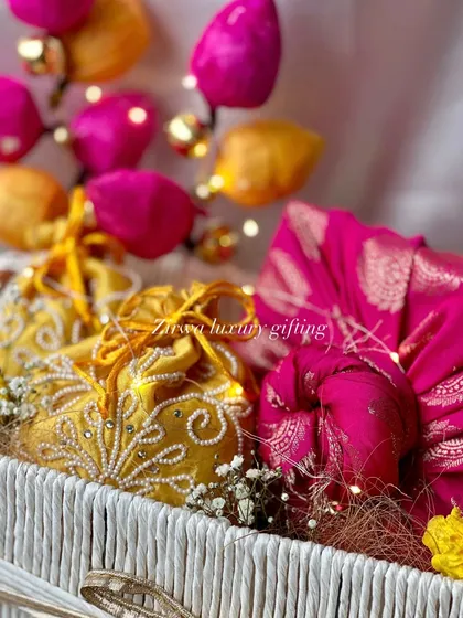 The fairy lights woven into this Lohri hamper add a magical glow. The bright pink and yellow potlis look even more beautiful under the warm light.