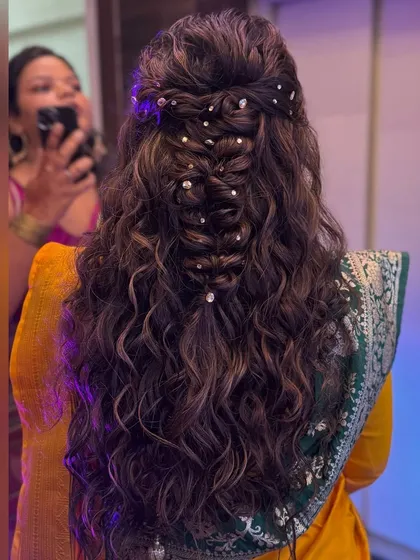 A detailed view of the braided half updo with shimmering gems. The combination of the braid and curls creates a beautiful texture that is both intricate and soft.