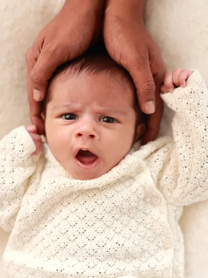 A sleepy yawn from a newborn, held securely by their dad's hands. Capturing these fleeting expressions is what makes newborn photography so special.