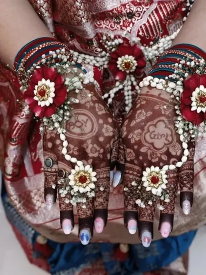 The final look of the baby shower mehndi, beautifully accessorized with floral jewelry. The design includes the names of the parents-to-be.