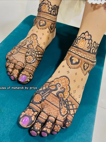 A close-up of a stained foot mehendi, showing the rich brown colour and the beautiful details of the peacock and floral design.