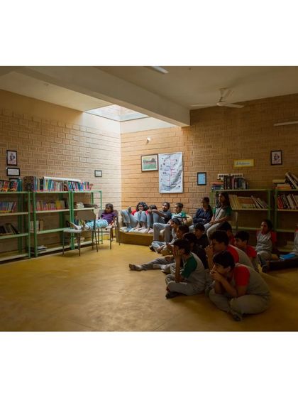Students gathered in the library at Buddhi School, illuminated by a large skylight. We use passive design strategies like top-lighting to bring natural, diffused light deep into the building, reducing the need for artificial lighting.