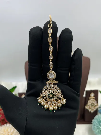 The 'Ziva' maang tikka with green accents.