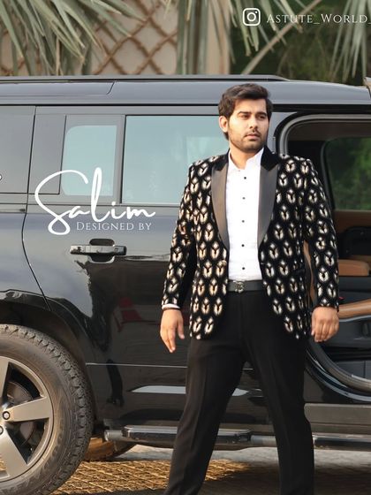 A client standing by a car, wearing a black velvet tuxedo jacket with a repeating gold foil pattern. The combination of velvet and metallic print creates a luxurious and eye-catching effect.