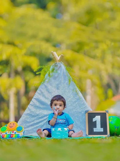 The start of a cake smash session in our outdoor teepee setup. The simple blue cake contrasts nicely with the green grass and white teepee.