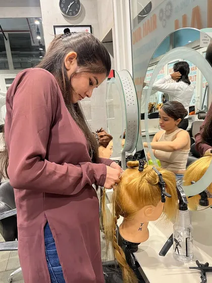 A student practices applying extensions, ensuring the bonds are secure and discreet.
