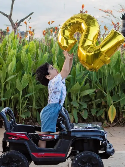 Reaching for the stars, or at least the birthday balloon. A candid, playful shot from a second birthday celebration with a toy jeep.