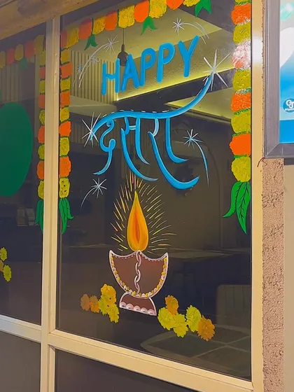 A simple yet elegant Dussehra greeting painted on glass, featuring a lit diya to symbolize light and hope.