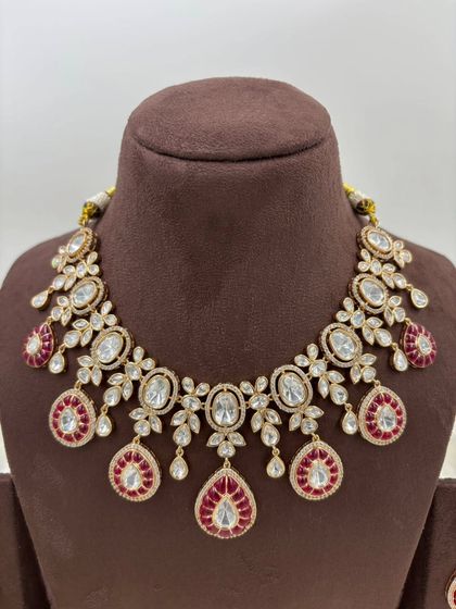 A beautiful Moissanite and AD necklace set with green or red Meenakari detailing. The combination of oval and teardrop stones gives this piece a unique and luxurious appeal.