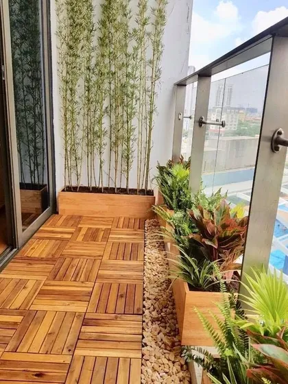 A clean, modern aesthetic can make a small balcony feel spacious and serene. Here, I used interlocking wooden deck tiles, custom wooden planters for bamboo to create a natural privacy screen, and a mix of tropical plants for a resort-like feel.